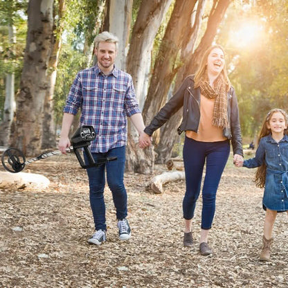 Family of three walking together in a park with trees and sunlight.