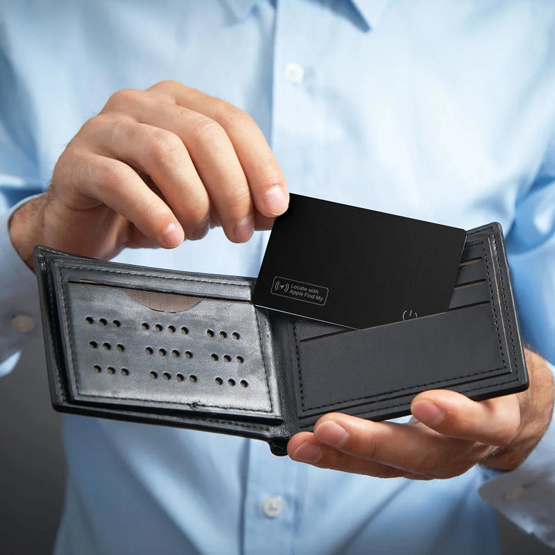 Person holding a black wallet with a IziPock Wallet Tracker Card inside, wearing a light blue shirt.