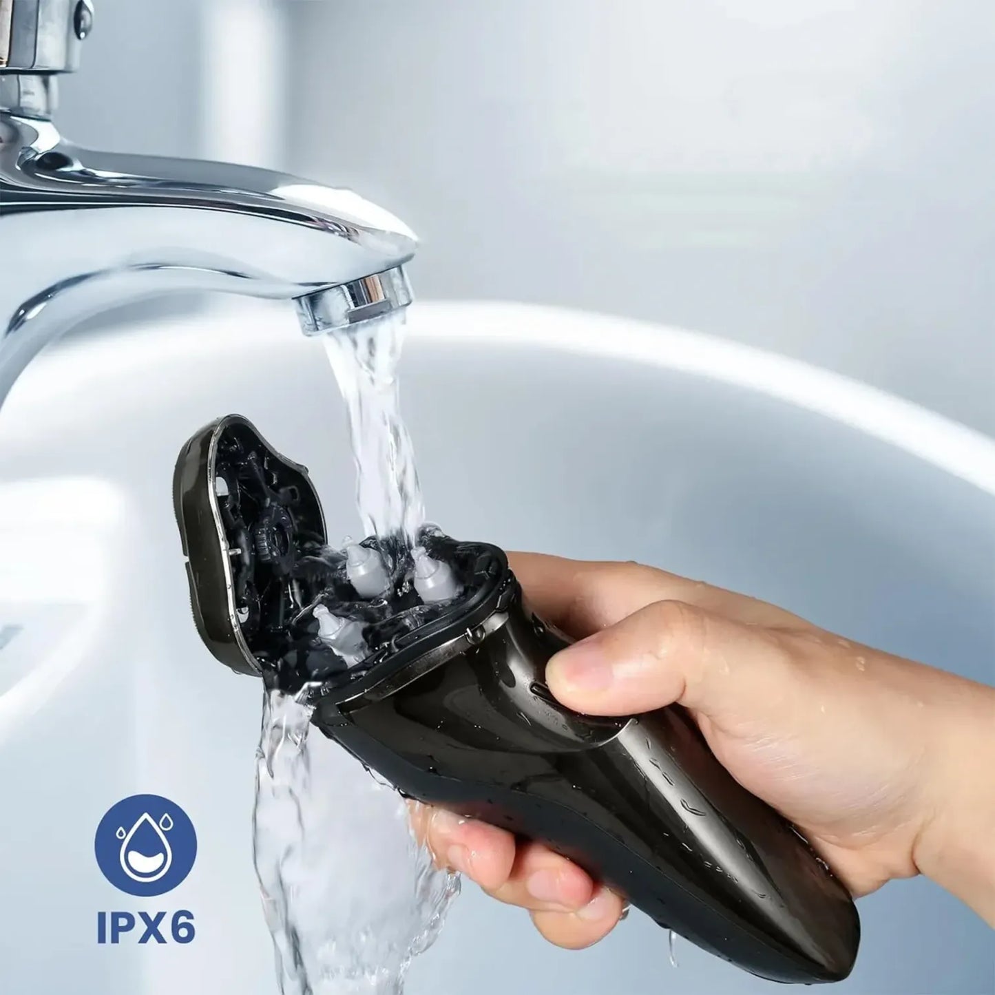 Hand holding a black Kozenix Shaver under running water from a faucet, with IPX6 rating logo.