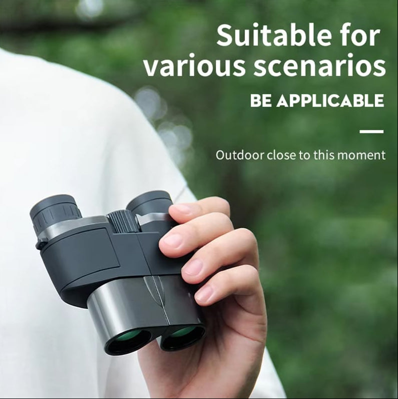 Hand holding MikoSpek Binoculars with a blurred green background