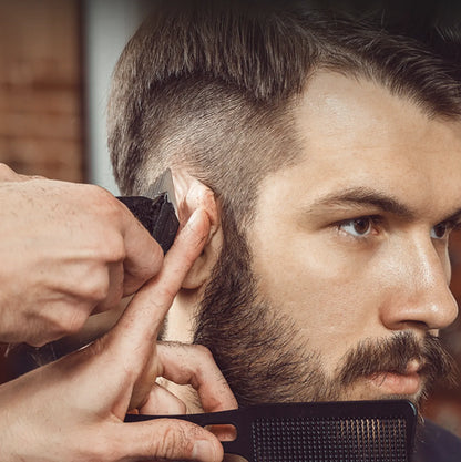 Barber trimming a customer's beard with a comb and Nordzens Hair Clipper in a close-up shot.
