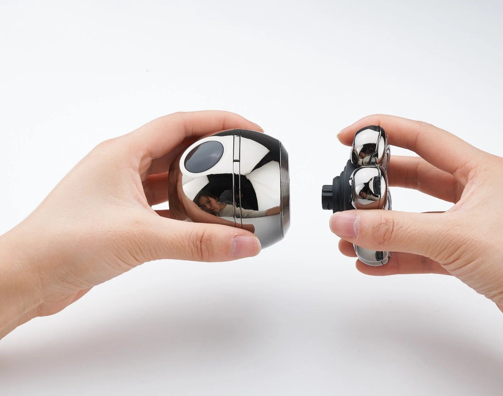 Two hands holding metallic cube-shaped objects against a white background