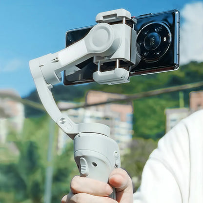 Hand holding a smartphone Puruxe Gimbal with a clear sky and blurred background