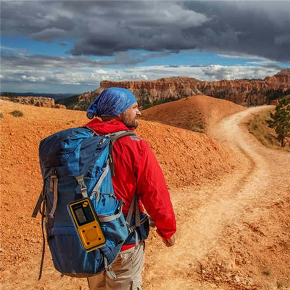 Hiker with a blue backpack and red jacket standing on a dirt path with a scenic landscape.