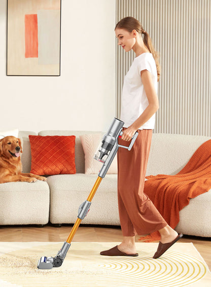 Woman using a drexen vacuum cleaner in a living room with a dog sitting on the couch.