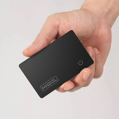 Hand holding a black rectangular IziPock Wallet Tracker Card with a power symbol on a light gray background